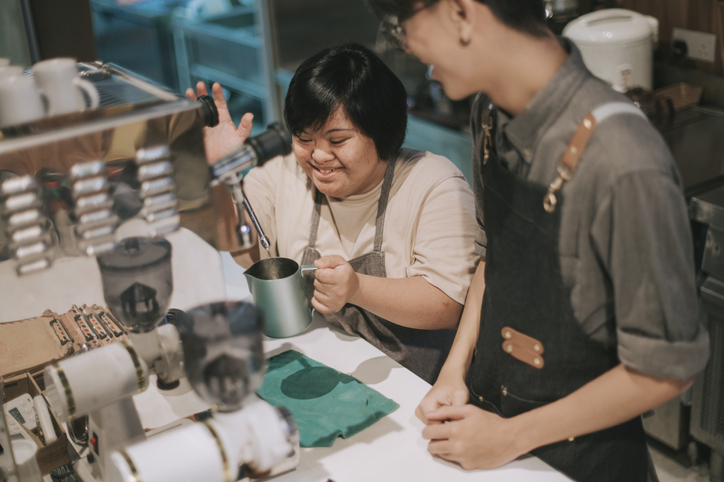 An Asian woman with Down Syndrome learning how to make coffee at a cafe